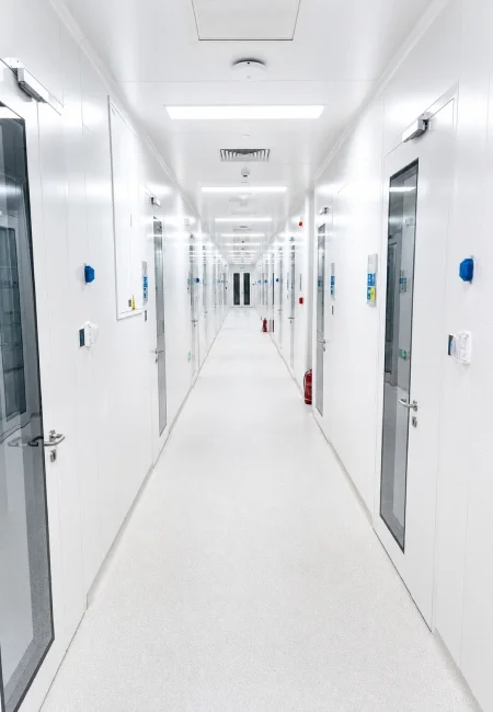 Pharmaceutical cleanroom corridor with smooth white chemical resistant wall panels and flush cleanroom doors