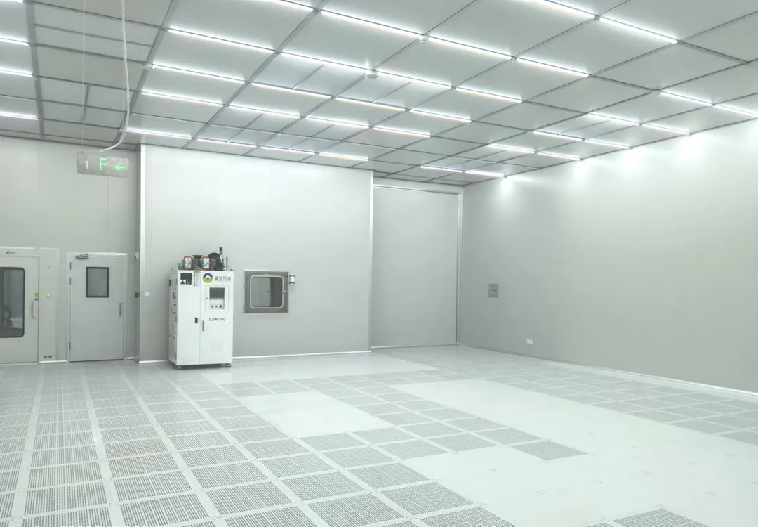 Interior of a completed modular cleanroom with grid ceiling lighting, sealed wall panels, pass box and perforated raised floor